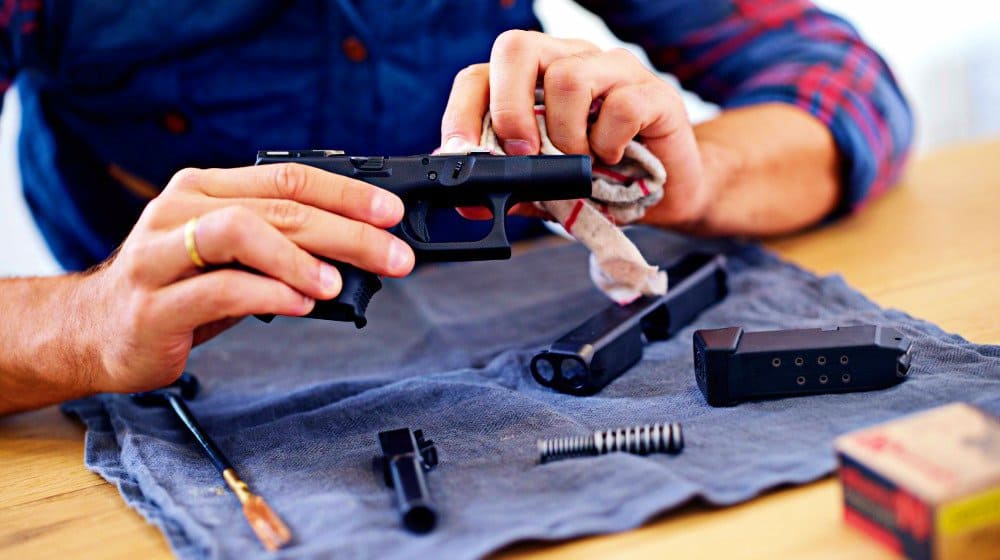 dismantled handgun being wiped with gun oil