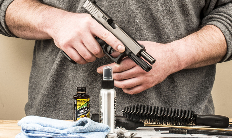 close-up photo of a man removing rust from a handgun with tools laid on the tables