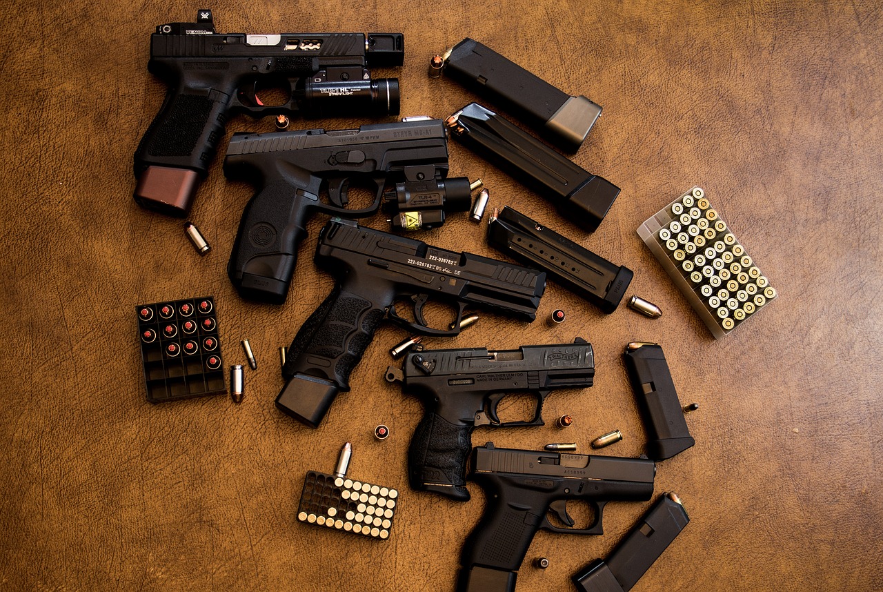 photo of 5 different handguns, magazines and three boxes of 9mm ammo