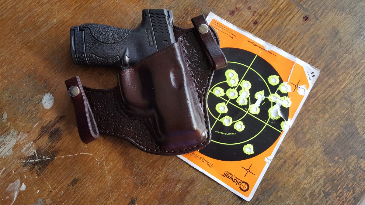 a compact handgun inside a leather holster on top of a target practice paper